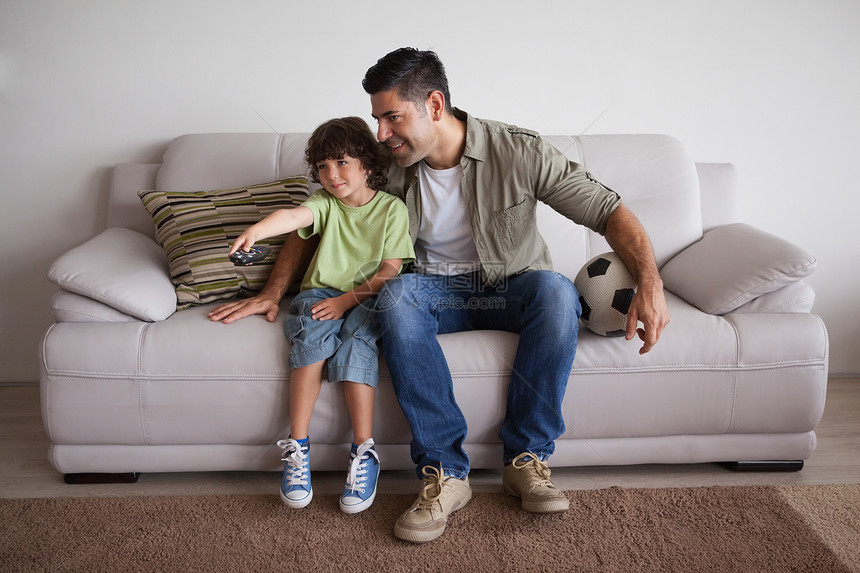 父亲和儿子在客厅看橄榄球电视遥控频道男人家庭软垫男生爱好公寓游戏孩子图片