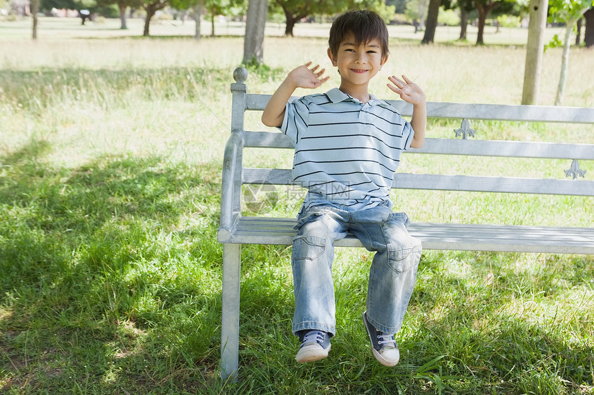 快乐的小男孩坐在公园的长凳上图片