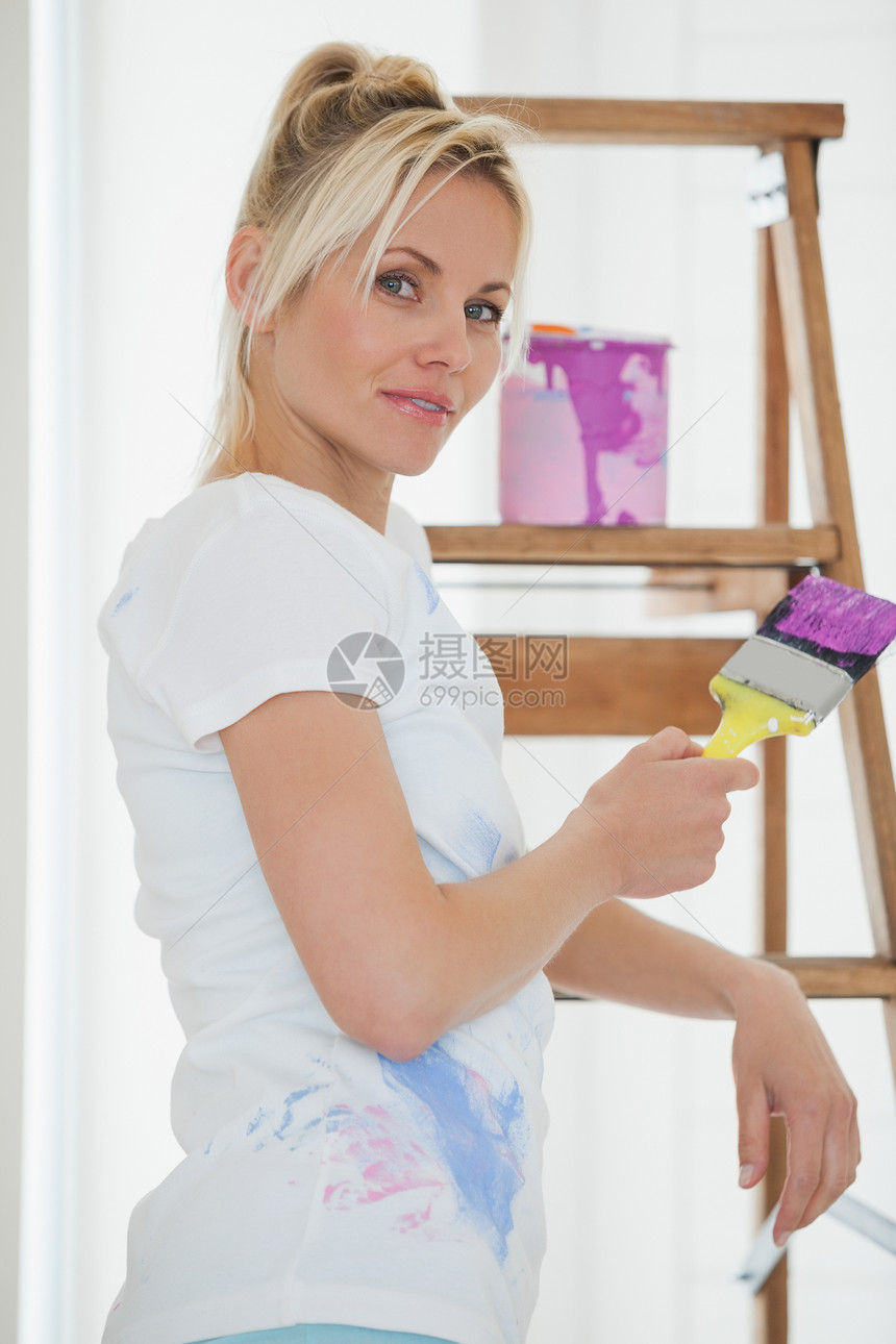 女人在新房子的梯子前拿着油漆刷子图片