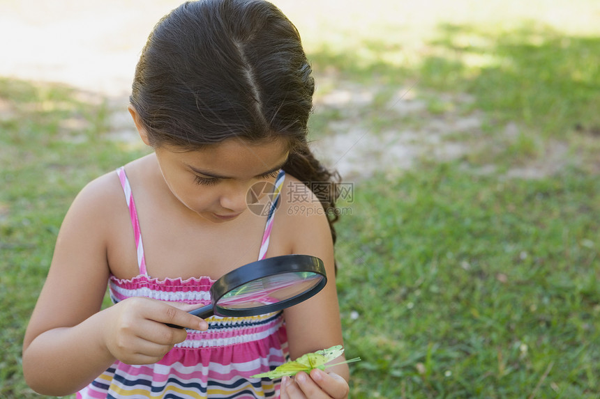 女孩在公园用放大镜检查一片叶子图片