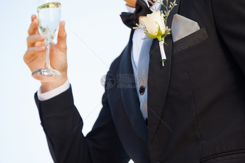 男性拿着香槟杯子时 在男性胸罩上献花的中间部分花朵图片
