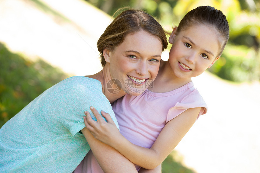 微笑的母亲在公园里拥抱她的女儿女孩双臂女性享受孩子快乐闲暇童年草地家庭图片