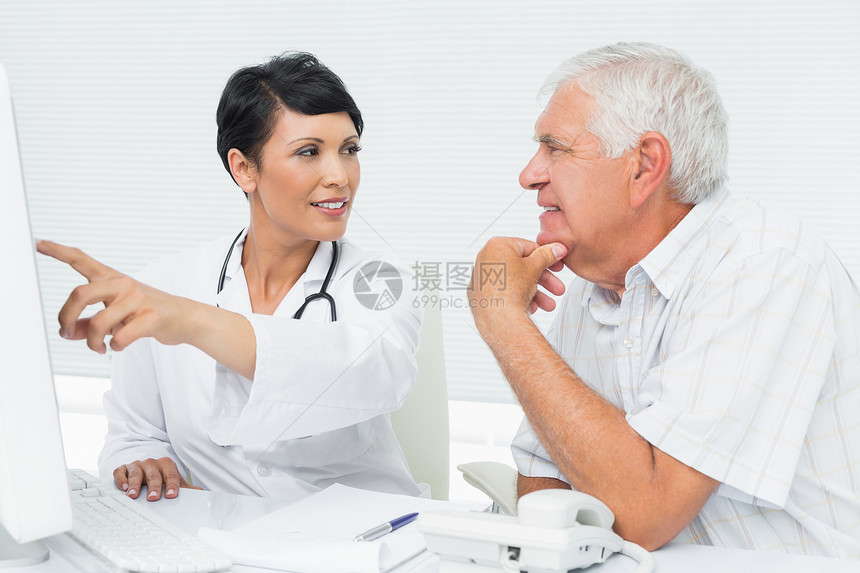 医生和男性病人在计算机上阅读报告的报告成人短发退休混血诊所治疗医师顾问桌子手指图片