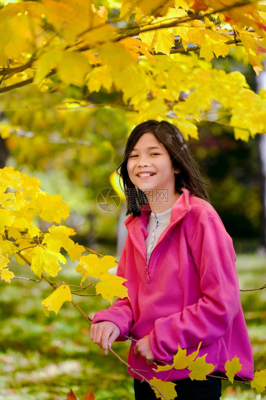 站在明日秋叶的露天树叶边上孩子混血女孩橙子黄色微笑混血儿季节粉色红色图片