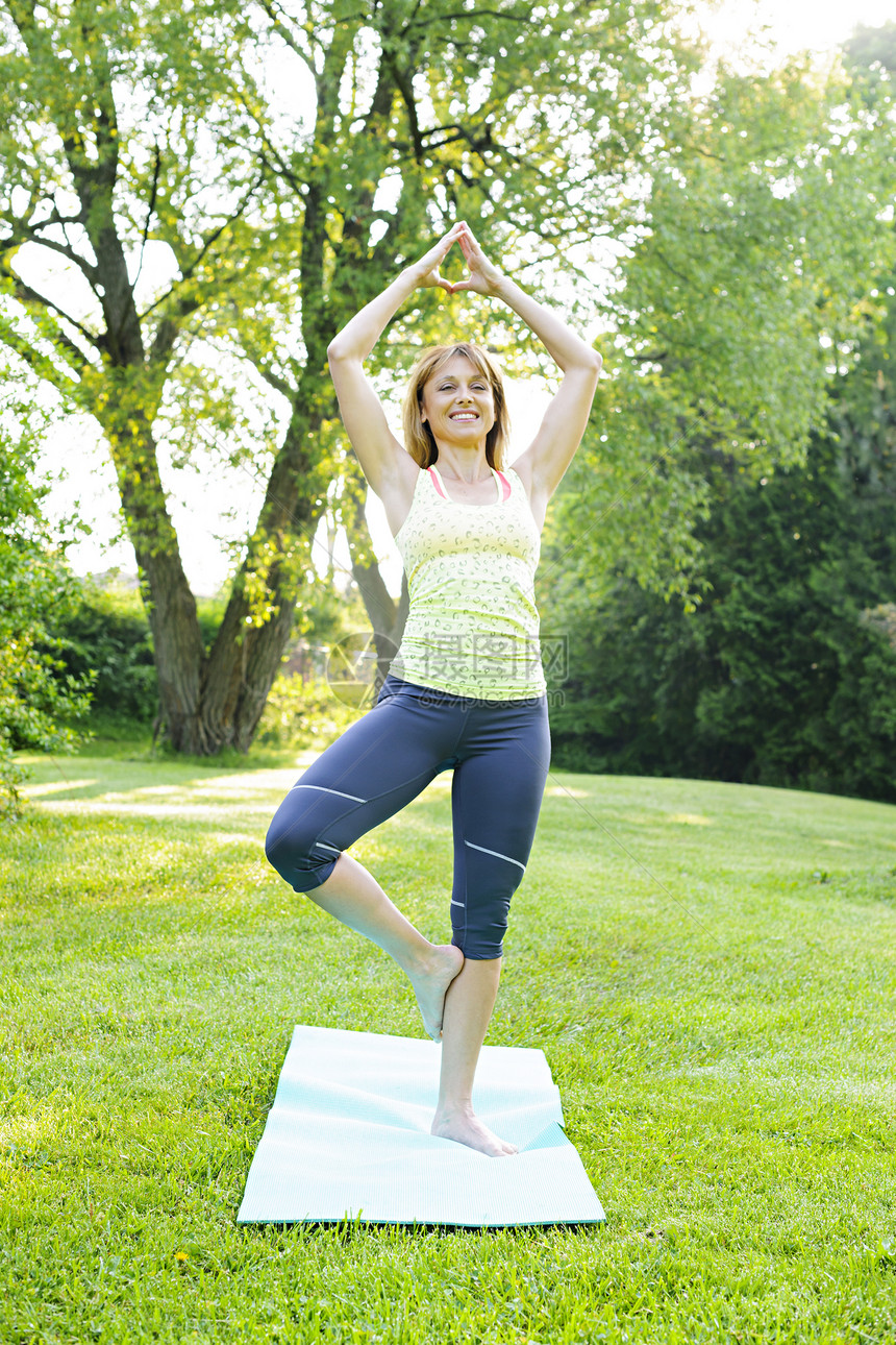 瑜伽树上的女人摆姿势平衡公园冒充运动讲师培训师金发女郎中年成人微笑图片