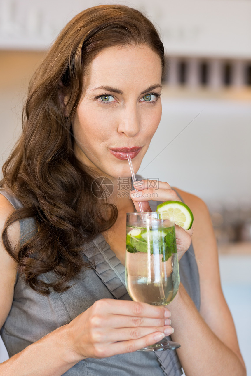 一个带着鸡尾酒杯 微笑的年轻女人的近身酒精女士女性闲暇头发棕色酒会稻草派对酒吧图片