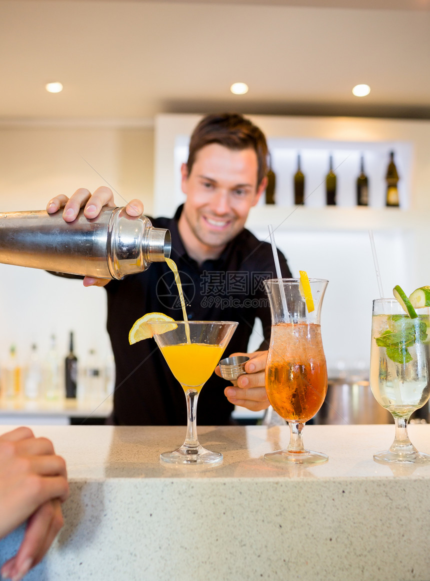 在酒吧柜台准备饮料时微笑的酒保酒精闲暇派对玻璃成人男人酒会前台男性图片