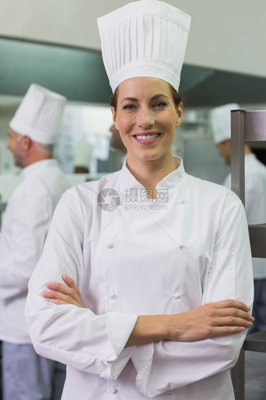 微笑的厨师看着摄影机 团队在后面工作男性女性酒店准备伙伴男人双臂成人快乐职员图片