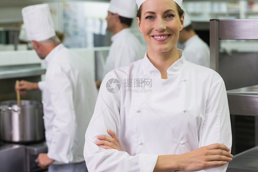 微笑的厨师看着摄影机 团队在后面工作职业搅拌烹饪男性快乐准备男人商业炉顶女士图片