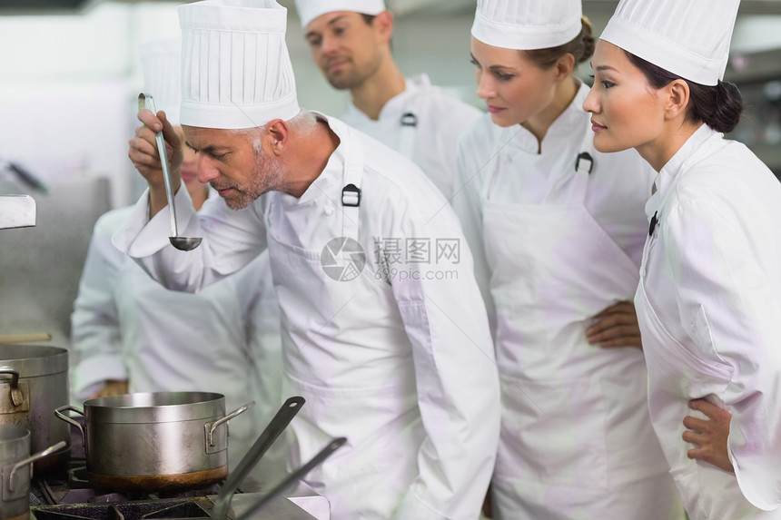 主管厨师在员工旁观时喝汤同事合作钢包餐厅酒店厨房工作混血职业准备图片