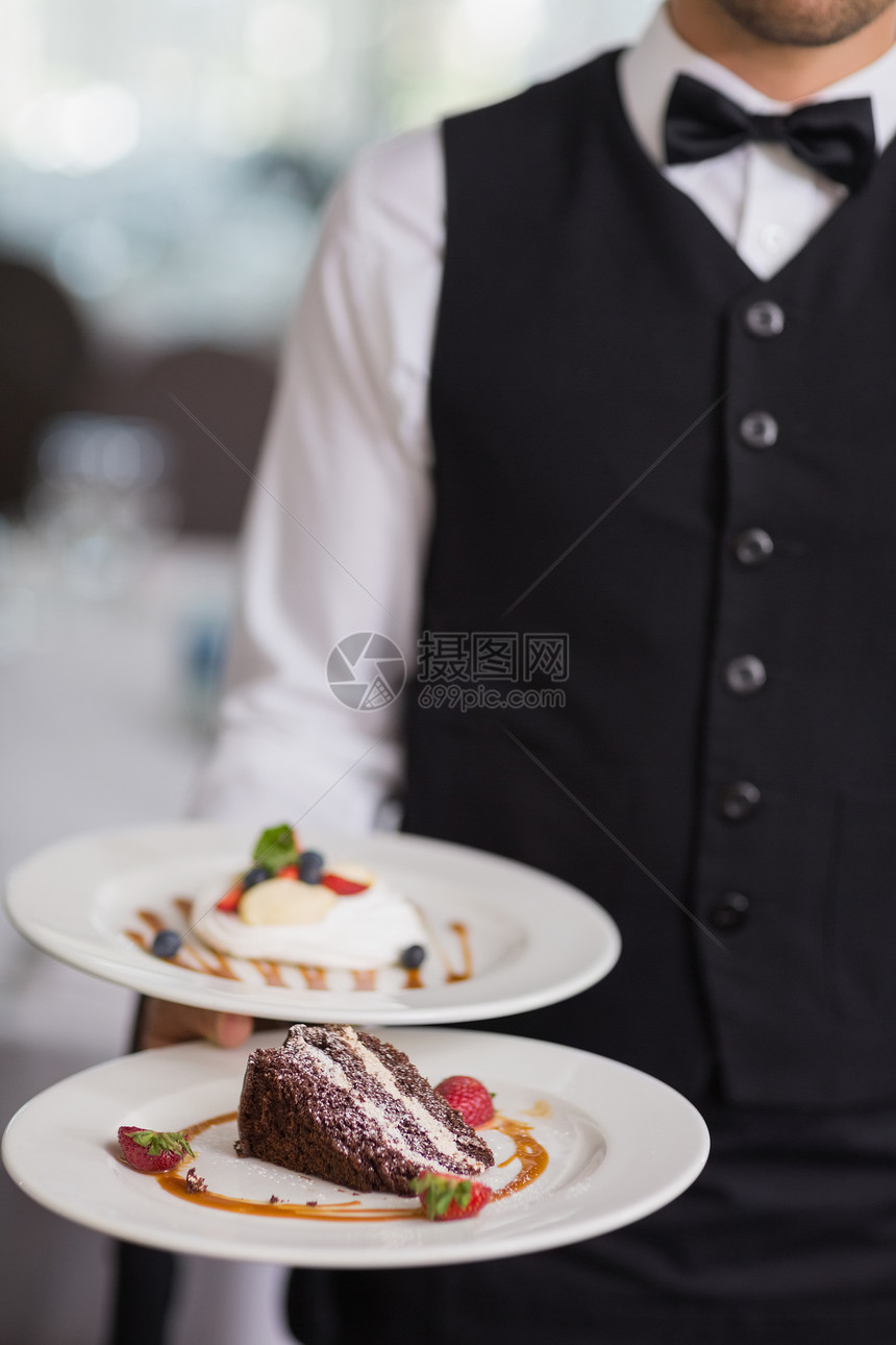 服务员显示两个甜点盘衬衫男人蛋糕马甲领结巧克力盘子餐厅酒店平衡图片
