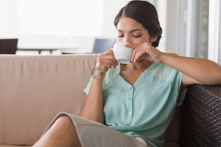 坐在沙发上喝咖啡的有想象力的女商务人士女性长椅头发混血咖啡杯女士商务阳台咖啡店思维图片