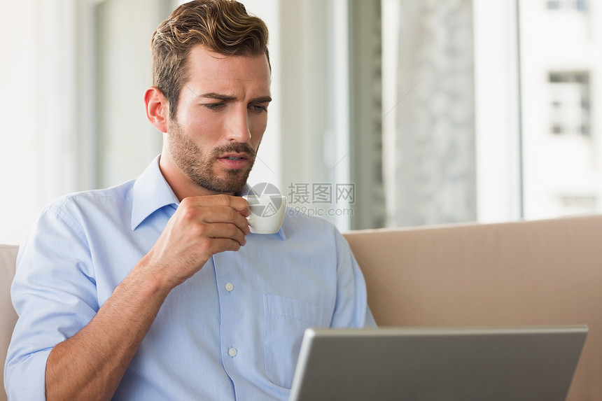 在笔记本电脑上喝咖啡的英俊商务人士人士咖啡店餐厅沙发男人商务露台咖啡专注杯子图片