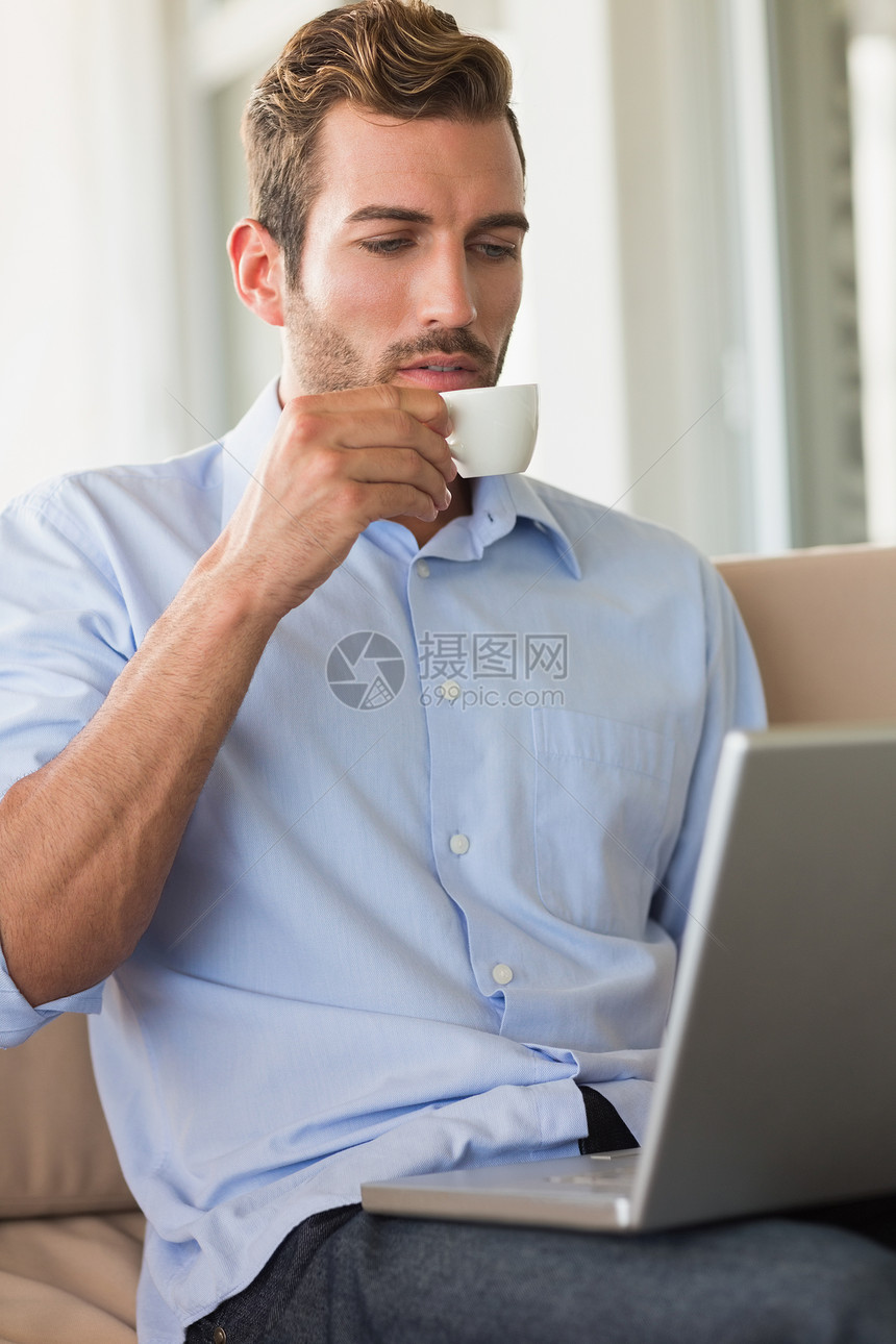 在笔记本电脑上喝咖啡的英俊商务人士沙发男性咖啡咖啡店阳台男人商务专注露台杯子图片