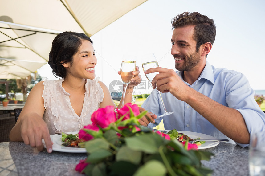 快乐的一对夫妇庆祝结婚纪念日 加香槟桌子裙子玫瑰纪念日闲暇混血玻璃露台奢华周年图片