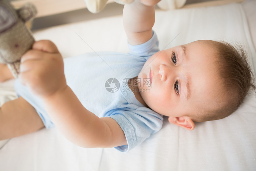 躺在婴儿床的婴儿宝宝男孩玩手机游戏房子家庭双手好奇心蓝色卧室服装住所用品玩具图片