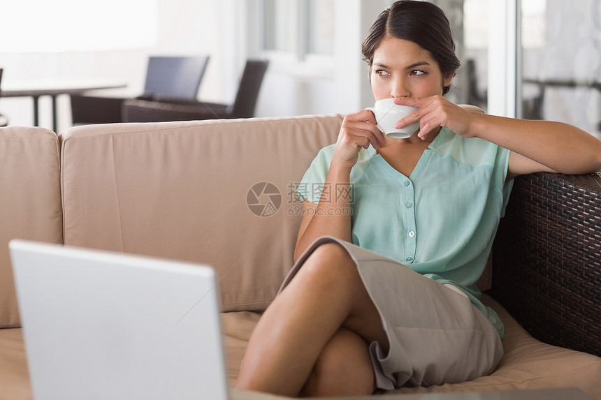 坐在沙发上喝咖啡的有想象力的女商务人士头发咖啡店混血黑发女性思维餐厅咖啡杯闲暇人士图片
