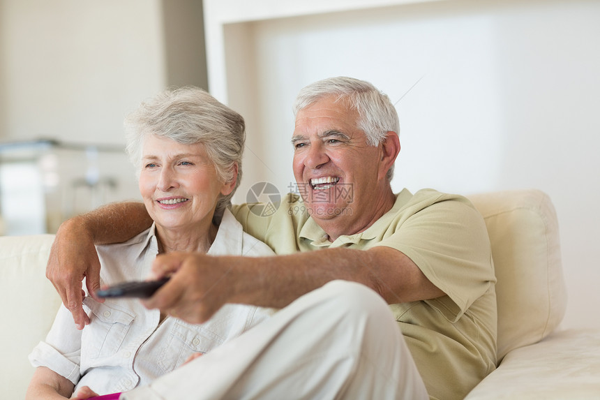 快乐的情侣在沙发上看电视遥控闲暇频道女士头发退休老年房子客厅男人图片