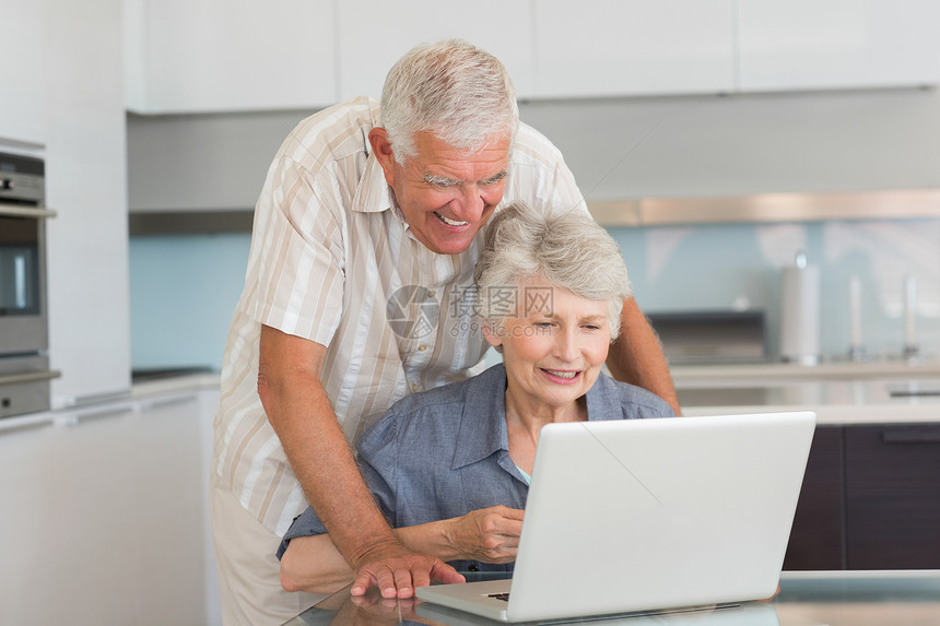 幸福的一对夫妇用笔记本电脑在桌子上头发闲暇技术家庭男人女士男性倾斜老年房子图片