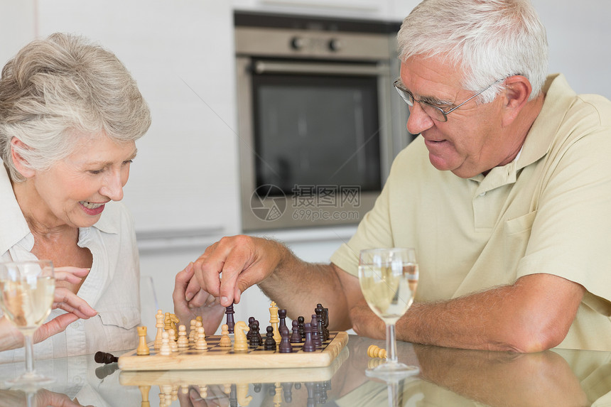 玩象棋和喝白酒的老夫妇微笑住所游戏男人棋盘专注头发竞赛房子男性厨房图片