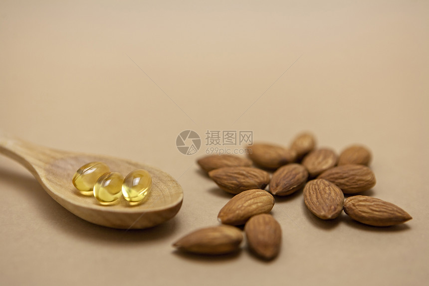 在棕色背景上隔绝的胶囊中的杏仁油脂肪坚果药品身体饮食草本食物纤维亚麻营养图片