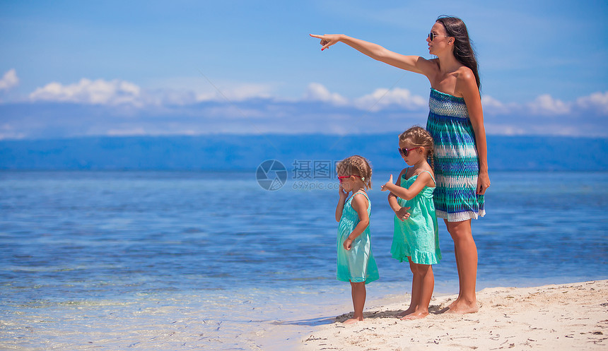 年轻母亲和两个女儿在阳光明日的奇异海滩上假期女士裙子沙漠情调女性海洋父母海岸海岸线图片