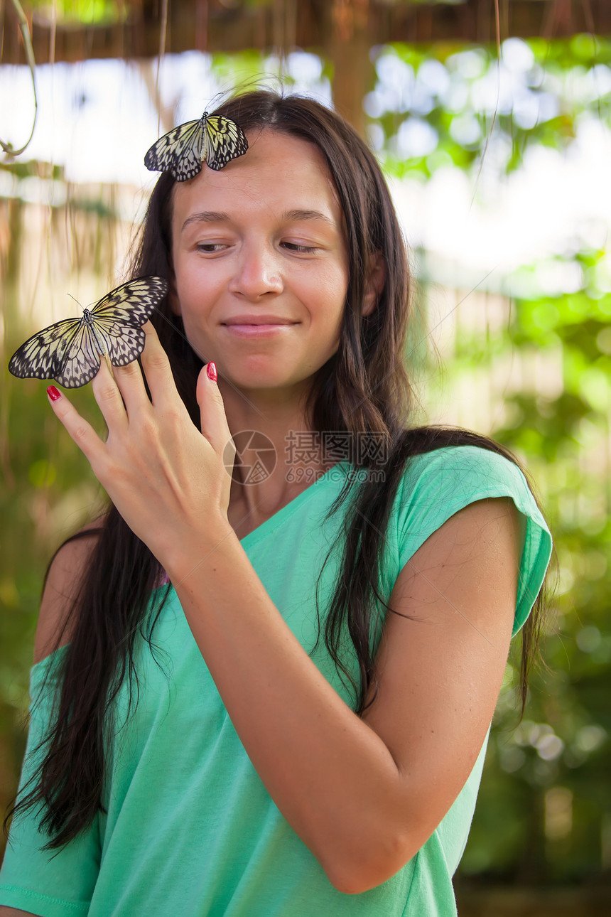 年轻女孩在自然花园里看蝴蝶图片