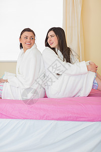 两个穿浴袍的朋友 坐在背对背坐着聊天背景图片
