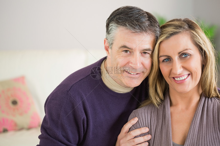 快乐的一对情侣看镜头家庭短发女性客厅长椅长发男性浅色微笑住所图片