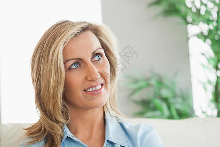 坐在沙发上思考的女人女士浅色头发公寓住所客厅家庭思维女性快乐背景图片
