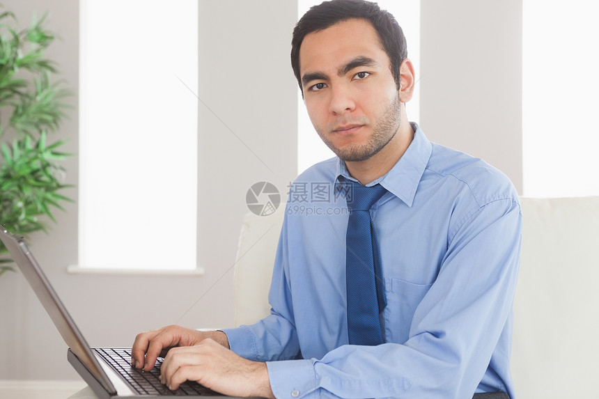坐在舒适沙发上时使用笔记本电脑的重度高级商务人士图片