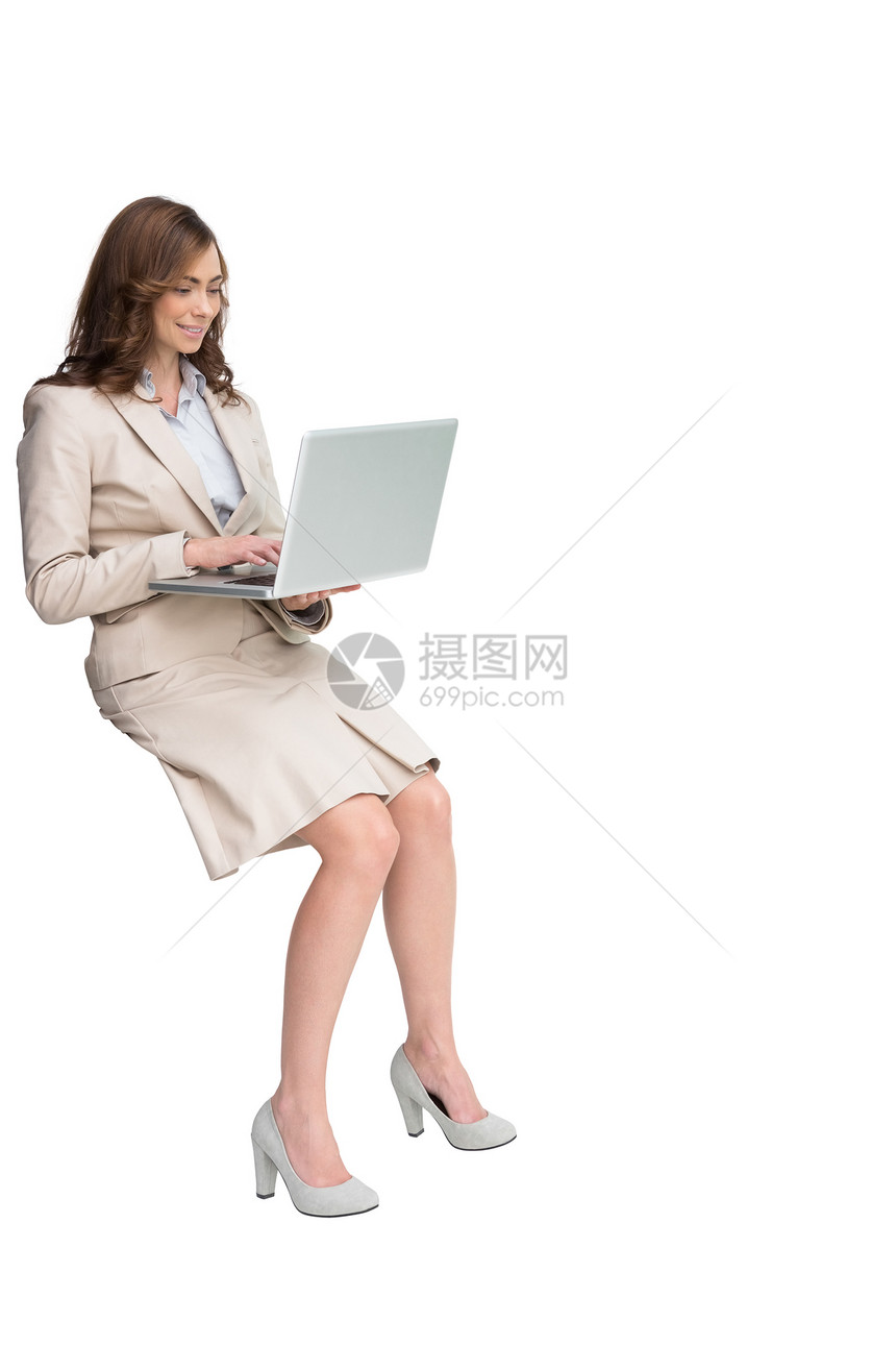 坐在并使用笔记本电脑的微笑女商务人士图片
