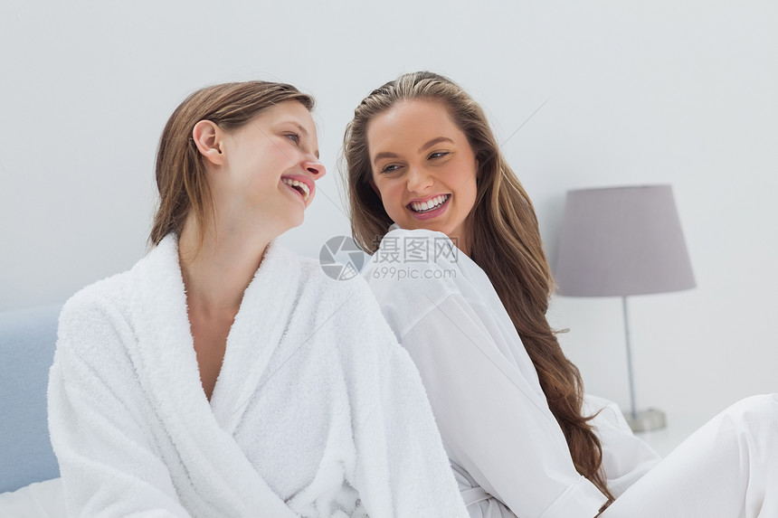 穿着浴袍坐在床上的快乐朋友图片