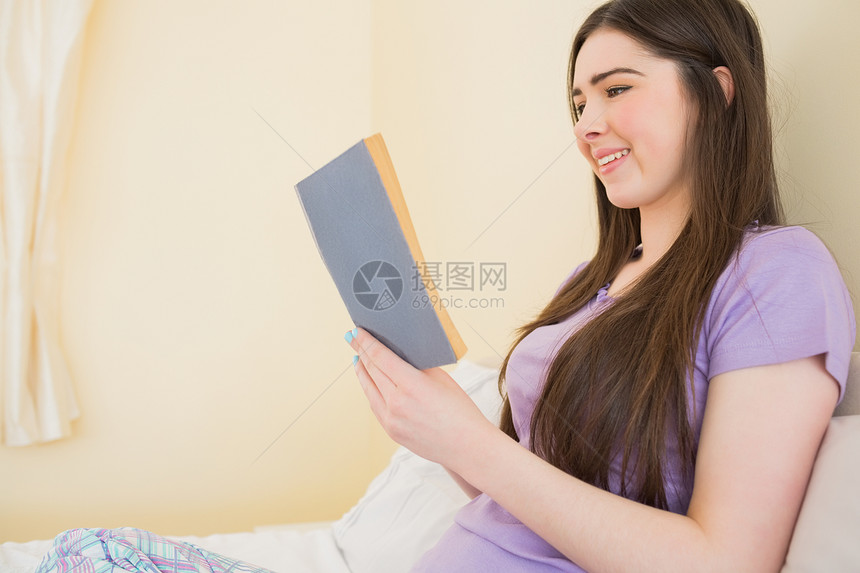 坐在床上看书的快乐女孩图片