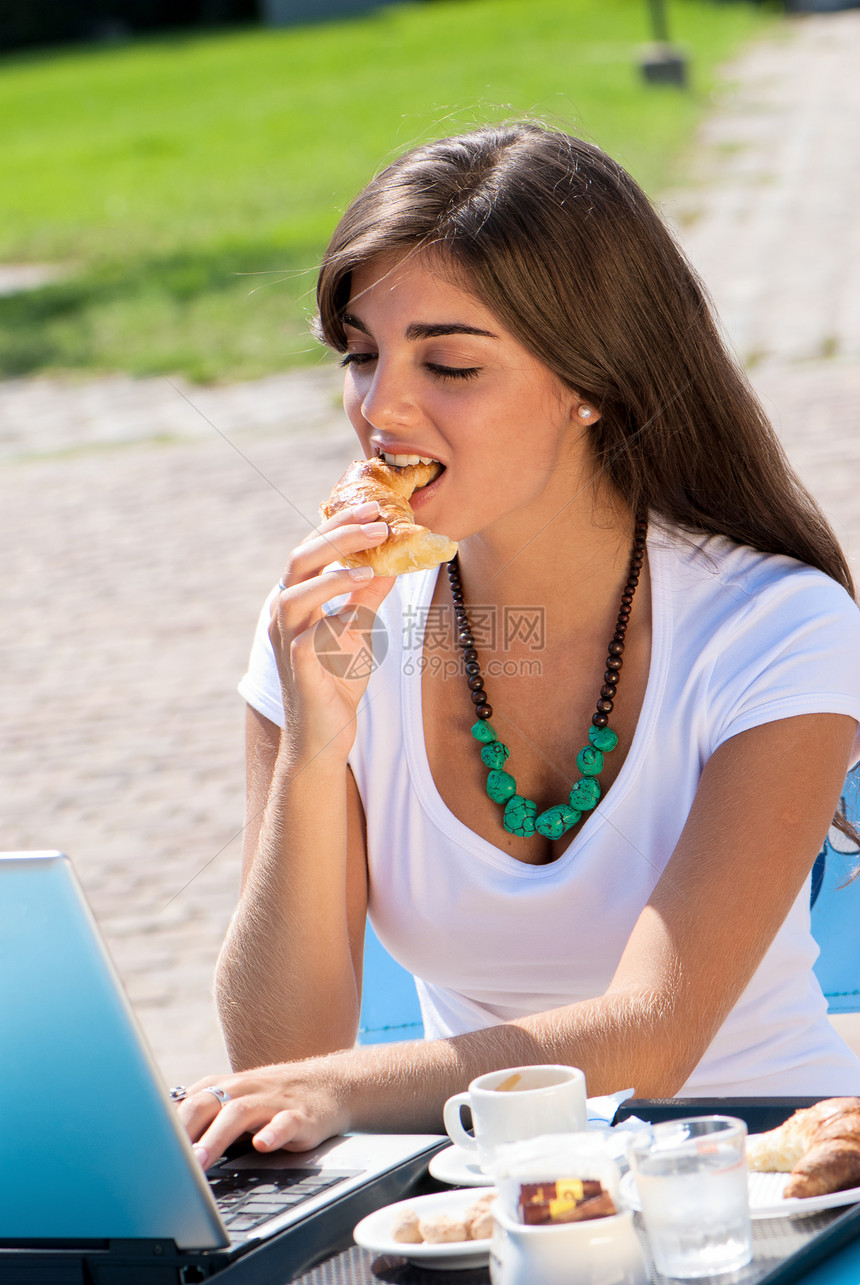 一个年轻有魅力的女人 拿着笔记本电脑坐在咖啡馆里咖啡店食堂午餐青少年缓刑犯女士早餐羊角实习生工作图片