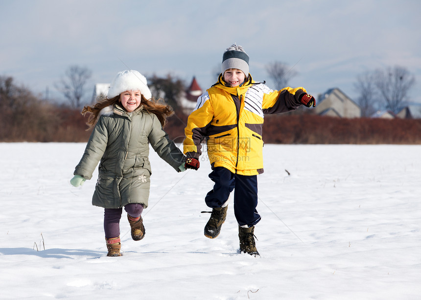 两个小孩在雪上奔跑 手举手微笑图片