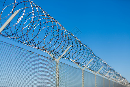 栅栏顶部的铁丝网链环蓝色倒钩监狱预防威慑安全金属拘留障碍背景