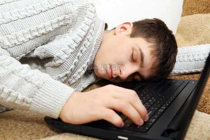 青少年在笔记本电脑上睡觉小伙子毛衣键盘小憩男性沙发瞌睡互联网房间游戏图片