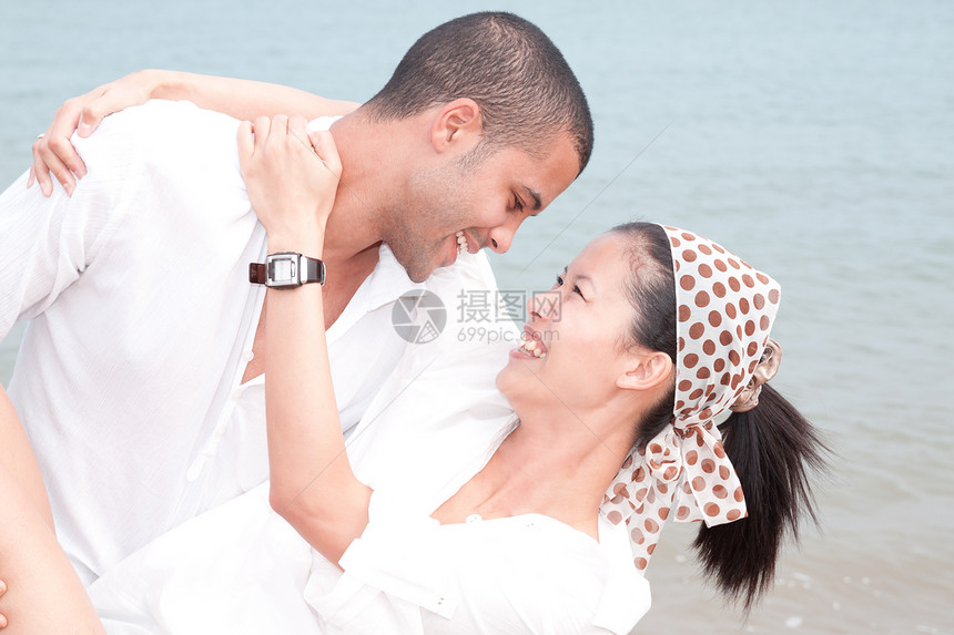 非洲男人和亚洲女人在海滩上的爱人女孩假期小猪感情乐趣女士夫妻女性男性蓝色图片