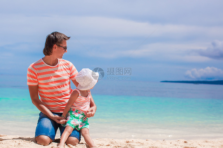 父亲和小女儿在白沙滩上放松男人女孩乐趣父母海洋爸爸情调假期孩子微笑图片