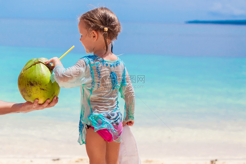 在异国海滩上配椰子牛奶的可爱小女孩肖像图片
