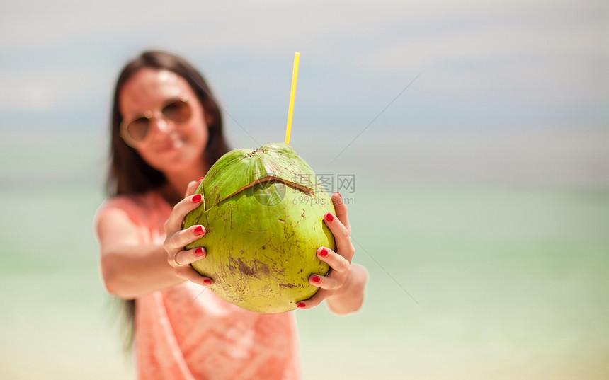 把椰子贴在年轻快乐女孩的手里海洋太阳镜围巾女士闲暇天空假期天堂围裙异国图片