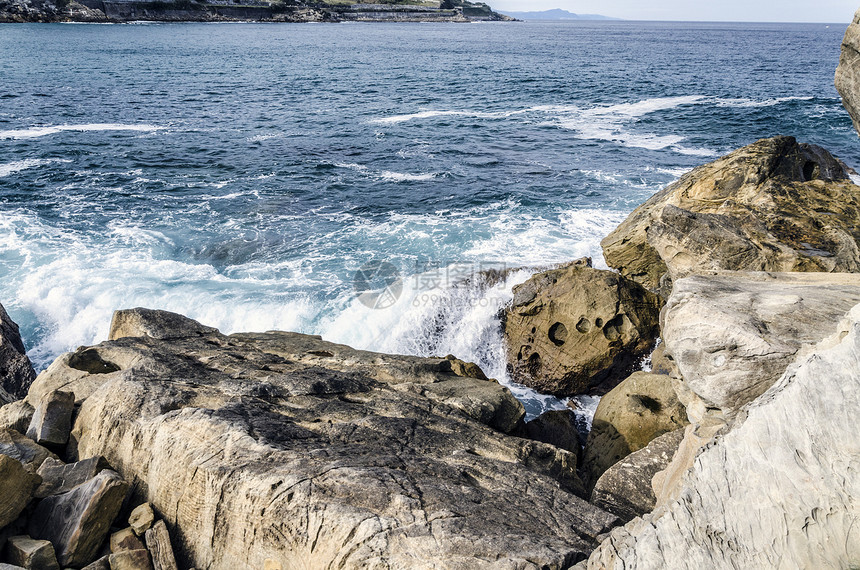 海洋中的岩石天空蓝色流动石头波浪黄色固体海浪图片