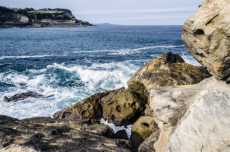 盖塔里亚海洋中的岩石海浪流动天空黄色波浪固体蓝色石头背景
