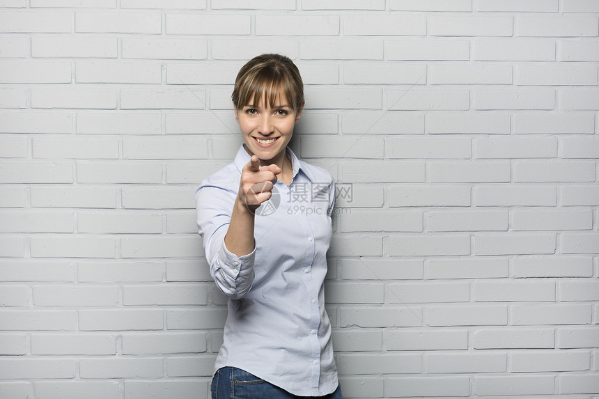 笑着可爱的女人在砖墙前用手指指着一根手指白色快乐工作室灰色学生女孩头发商务姿势手势图片