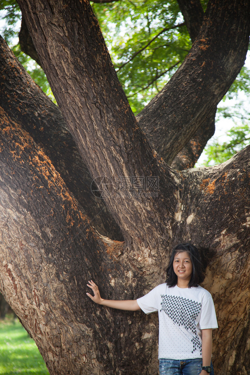 年轻女人站在一棵大树下绿色头发场地晴天女性生活女孩草地女士公园图片