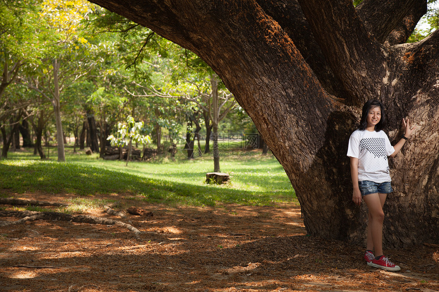 年轻女人站在一棵大树下生活绿色公园头发女士场地草地女孩晴天女性图片