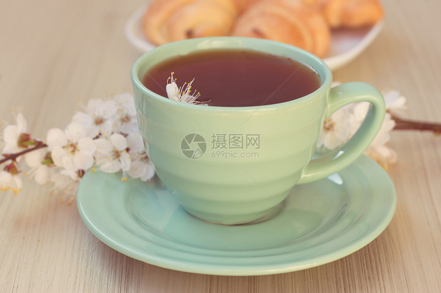 茶杯和羊角面包 在开花的树枝附近食物盘子花朵饮料飞碟牛奶咖啡桌子液体香气图片