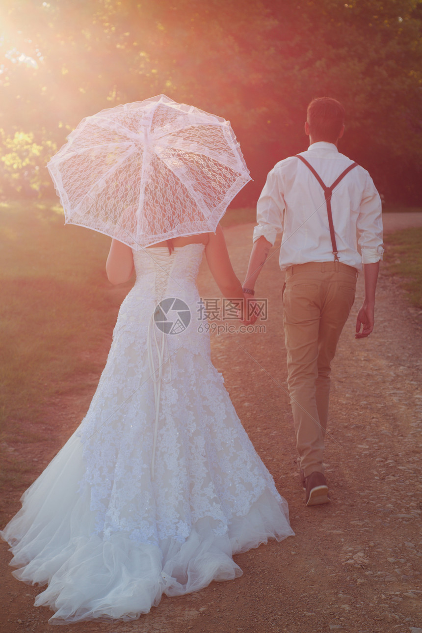 新娘和新郎走入日落女孩面纱庆典男人仪式女士花朵裙子婚礼套装图片