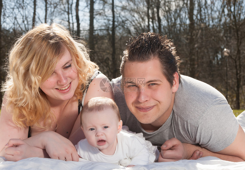 年轻家庭的肖像父亲公园婴儿快乐新生喜悦拥抱草地童年夫妻图片
